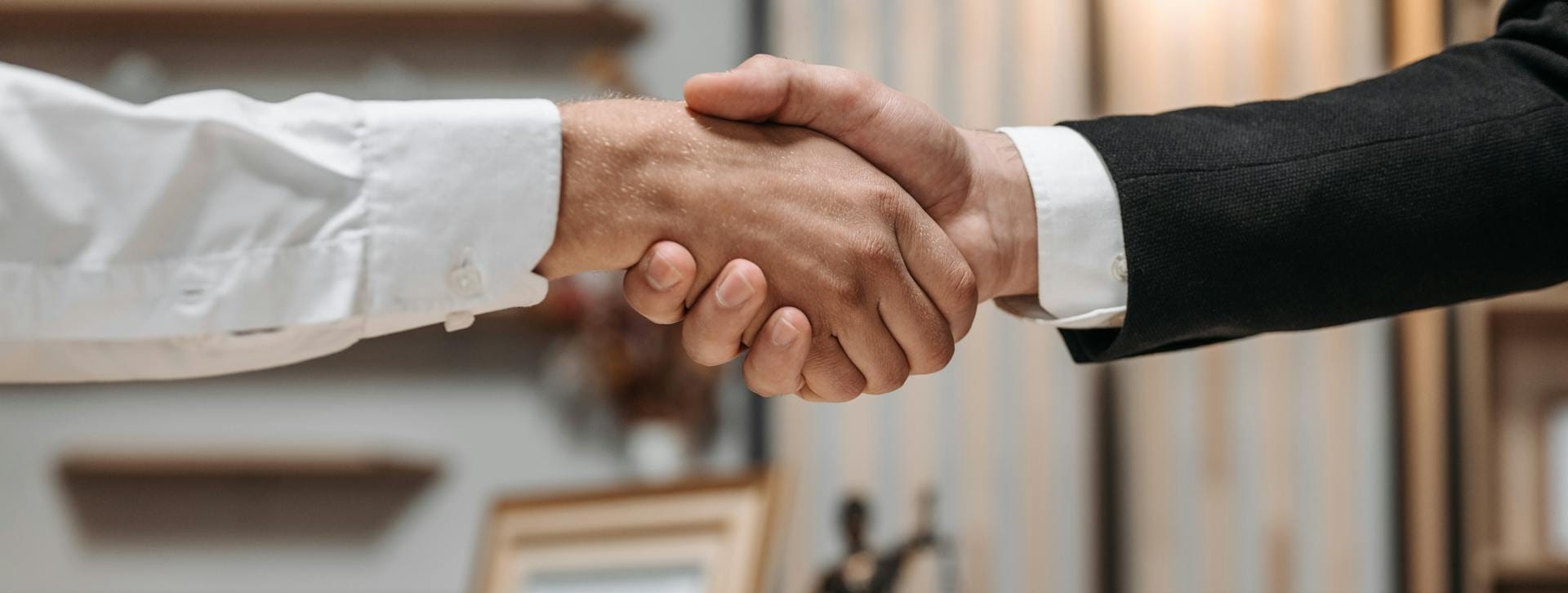 Dwie osoby uściskają dłonie nad biurkiem w biurze