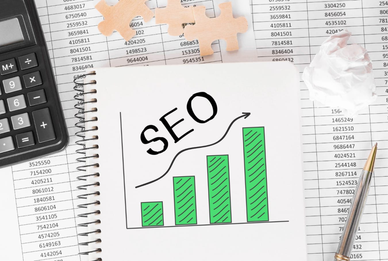 Notatnik z wykresem SEO, kalkulator, długopis i kartka z cyframi