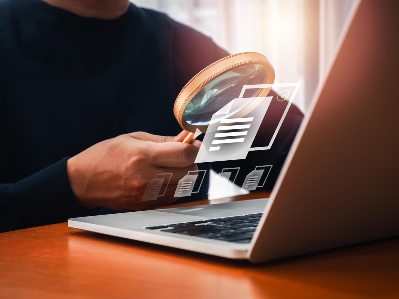 Osoba z lupą przy laptopie z ikonami dokumentów